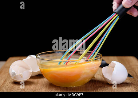 Whipped egg yolks in a glass bowl on a wooden cutting board Stock Photo