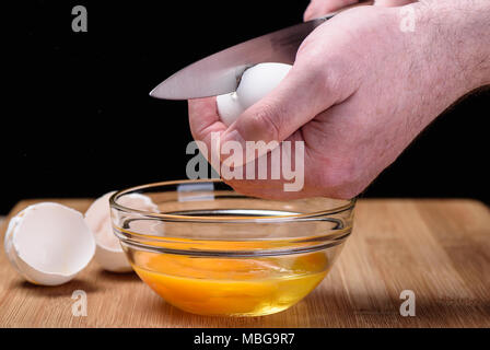 Destruction of a chicken white egg with a knife in male hands Stock Photo