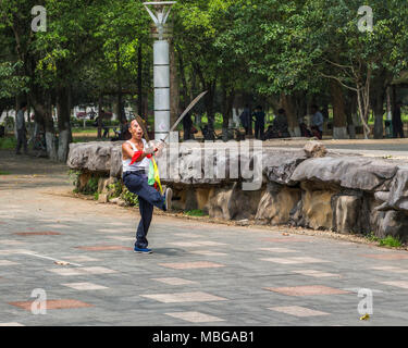 A Chinese man wields two swords as he practises martial arts in Yangshuo Park, Yangshuo, China. Stock Photo