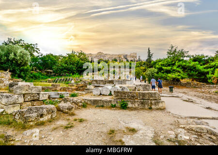 Tourists visit the ancient Agora at the base of the Acropolis Hill with the ancient Parthenon in view on a hazy afternoon in Athens Greece Stock Photo