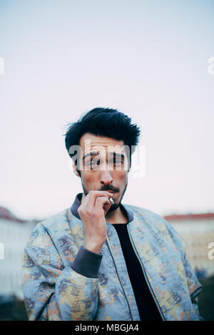 portrait of young cool arab man smoking a cigarette outdoors in urban environment Stock Photo