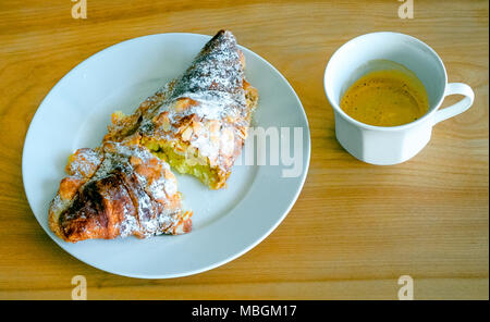 Almond croissant with cup of espresso on a blond wooden table Stock Photo