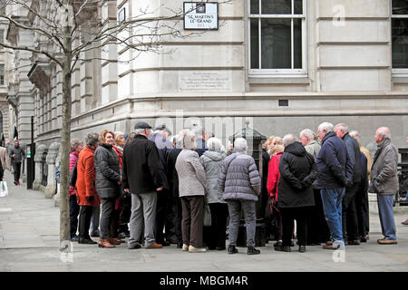 A tour group of elderly people seniors looking at a replica Penfold Victorian Post Box on St Martin's Le Grand in the City of London UK  KATHY DEWITT Stock Photo