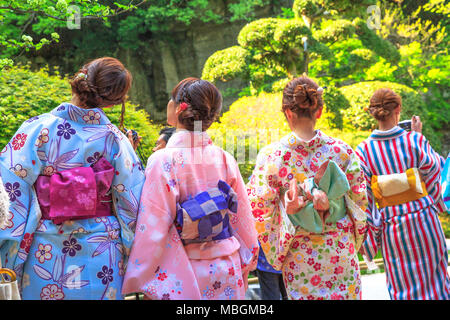 Kamakura, Japan - April 23, 2017: back of four Japanese ladies in zen garden, in traditional pink kimonos, admiring green zen garden in the nature of Takera Hokoku-ji Temple of Kamakura. Stock Photo