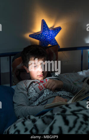 UK,Surrey.10 years boy reads in bed Stock Photo