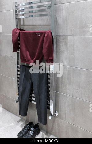 UK Getting ready for school,Primary boys school uniform  getting dry on bathroom towel rail radiator-side view Stock Photo