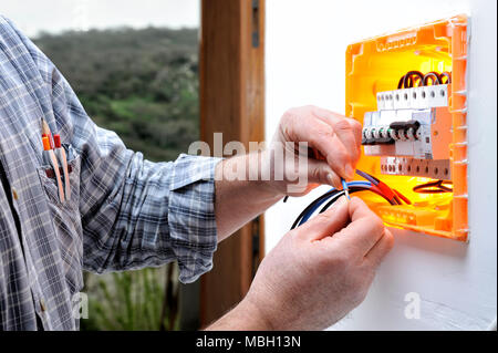 Electrician technician at work on a residential electric panel, prepares the wire with his hands Stock Photo