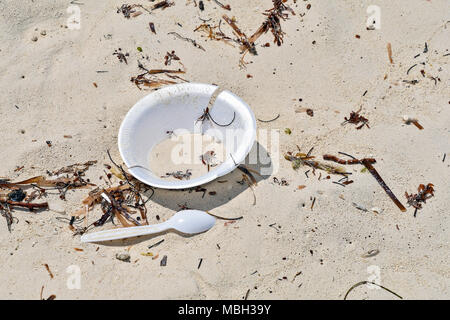 discarded plastic spoon and polystyrene foam dish on beach sand Stock Photo