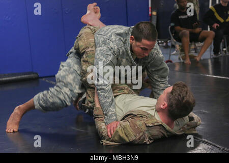 U.S. Army Spc. Nathaniel Mercado, (top) assigned to the 55th Signal Company (Combat Camera) is in Spc. Casey Dinnison's (bottom) guard during the Basic Combatives Course at Gaffney Fitness Center located at Fort George G Meade, Maryland, Dec 13, 2017. The Army combatives program enhances unit combat readiness by building Soldiers' personal courage, confidence, and resiliency as well as their situational responsiveness to close quarter threats in the operational environment. Stock Photo