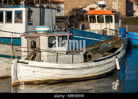 Small fishing boat moored outside another fishing boat on fine evening in harbor. Location Gronhogen on Oland, Sweden. Names and logos removed. Stock Photo