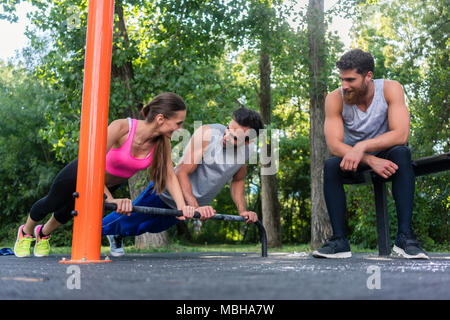 Young determined couple in love doing push-ups together in park Stock Photo