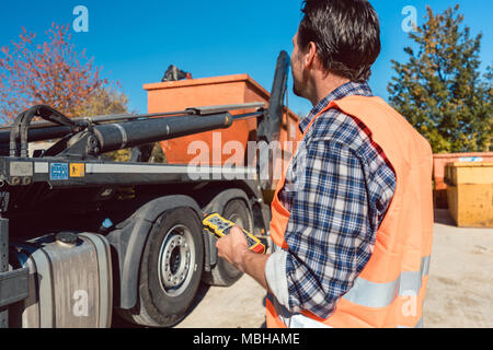 Worker on construction site unloading container for waste from truck Stock Photo
