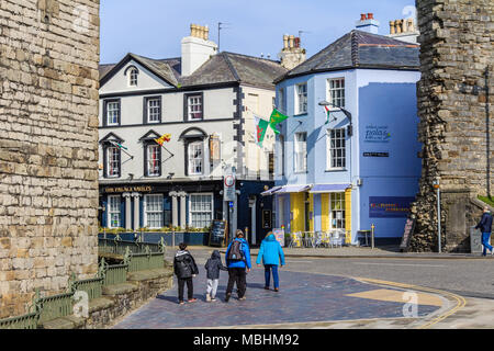 Family of holidaymakers walking up Castle Hill in town centre beside town walls, Caernarfon, Gwynedd, Wales, UK. Stock Photo