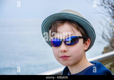 A portrait of an 8 year old boy wearing sunglasses and a sun hat. Stock Photo