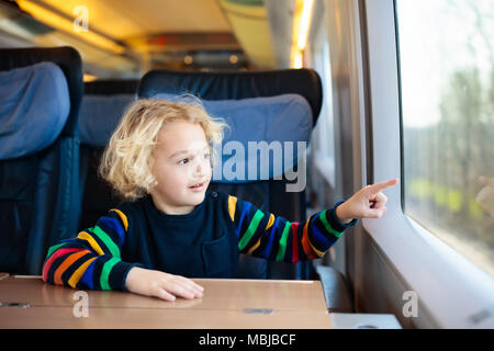 Child traveling by train. Little kid in a high speed express train on family vacation in Europe. Travel by railway. Children in railroad car. Kids in  Stock Photo