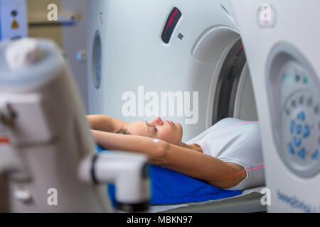 Pretty, young woman goiing through a Computerized Axial Tomography (CAT) Scan medical test/examination in a modern hospital (color toned image; shallo Stock Photo