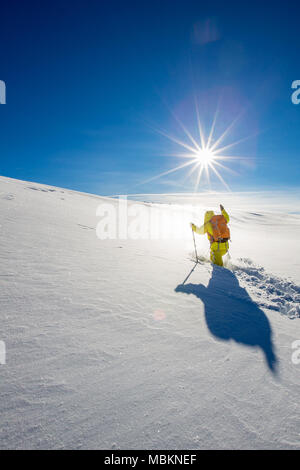 High altitude mountain explorer walking through deep snow in high mountains on a freezing winter day Stock Photo