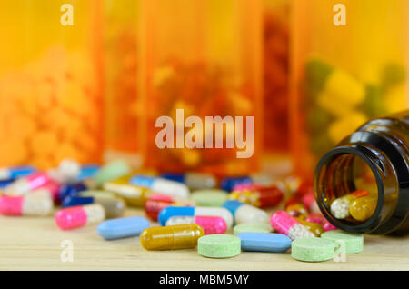 Colorful of oral medications on pine wood table with amber medicine bottle as background. Stock Photo