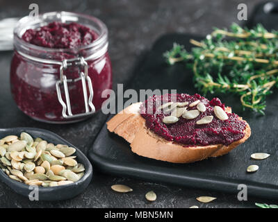 Bread with beetroot pesto or hummus,with pumpkin seeds and fresh thyme.Homemade beet pesto sauce in glass jar. Ideas recipes for healthy vegetarian detox diet food.Copy space for text. Selective focus Stock Photo