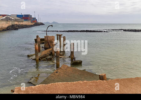 An old abandoned and collapsed Fishing Pier alongside the Sea wall of the new Modern Port on Sao Tome Island in West Africa. Stock Photo