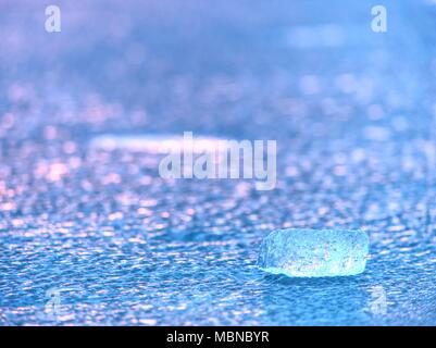 Shiny cold ice pieces on clear ice floe. Structure of natural ice in selective focus photograph.  Vivid colors of polar sunset. Stock Photo