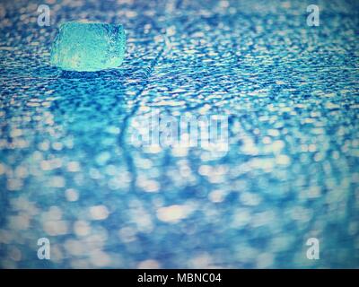 Shining cracked ice floe drifts on iceberg in blue lagoon.  Vivid warm colors of evening sun. Extreme low angl eview. Stock Photo