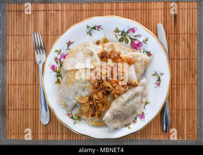 Dumplings with onions on plates, a traditional dish of Polish cuisine. Stock Photo