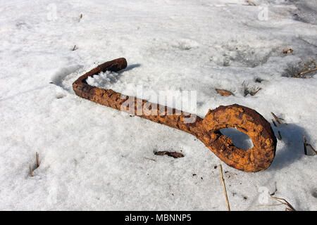 rusty old metal hook on snow Stock Photo