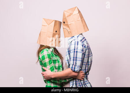 love, family and relationship problems concept - unhappy couple covering their sad faces with paper bag over white background. Stock Photo