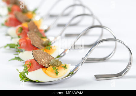 Truffle appetizers with eggs, ham rolls, capers and cress on party spoons Stock Photo