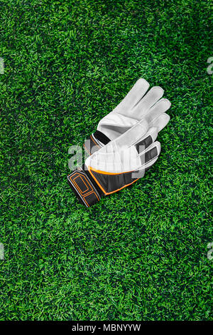 Gloves of the goalkeeper, football player, athlete, white, black, orange on a green lawn. Place for the inscription, rest, break, timeout, fatigue. Af Stock Photo