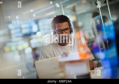 Focused creative businessman with headphones working at laptop in office Stock Photo