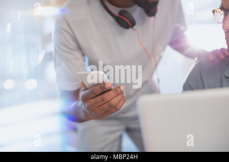 Close up creative businessman showing smart phone to colleague Stock Photo