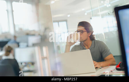 Creative businessman drinking coffee, working at laptop in office Stock Photo
