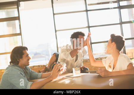 Excited entrepreneurs high-fiving in office meeting Stock Photo