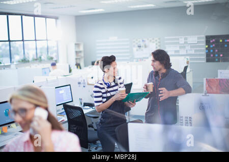Creative business people drinking coffee and talking in office Stock Photo