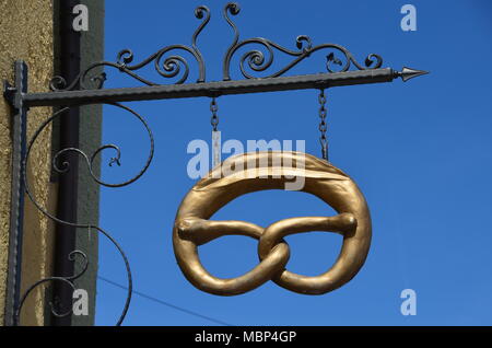 an antique metallic shop-sign in a shape of a golden pretzel in the old city of Füssen, Bavaria, Germany Stock Photo