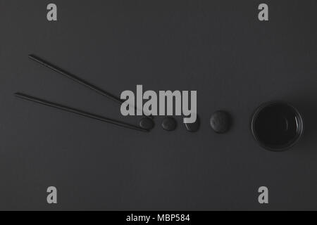 creative flat lay composition of chopstick with chinese tea cup and pebbles on black Stock Photo