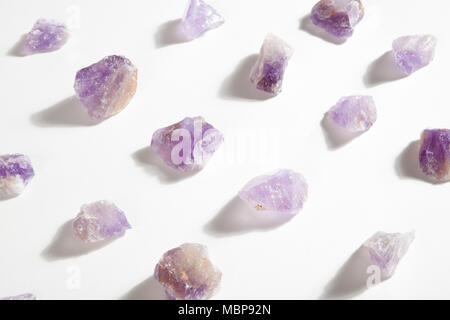 several pieces of raw amethyst lined up on a white background. Minimal color still life photography. Stock Photo