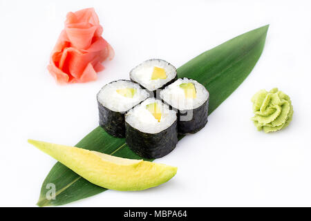 Delicious fresh mini-rolls with avocado and cheese on a banana leaf. Sushi rolls on a white background with ginger and wasabi. The Japanese menu. Stock Photo