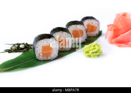 Delicious fresh mini-rolls with salmon on a banana leaf. Sushi rolls on a white background with ginger and wasabi. The Japanese menu. Stock Photo