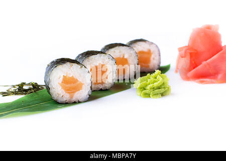 Delicious fresh mini-rolls with salmon on a banana leaf. Sushi rolls on a white background with ginger and wasabi. The Japanese menu. Stock Photo
