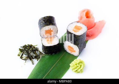 Delicious fresh mini-rolls with salmon on a banana leaf. Sushi rolls on a white background with ginger and wasabi. The Japanese menu. Stock Photo