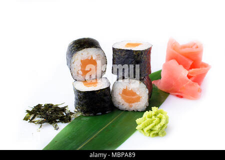 Delicious fresh mini-rolls with salmon on a banana leaf. Sushi rolls on a white background with ginger and wasabi. The Japanese menu. Stock Photo