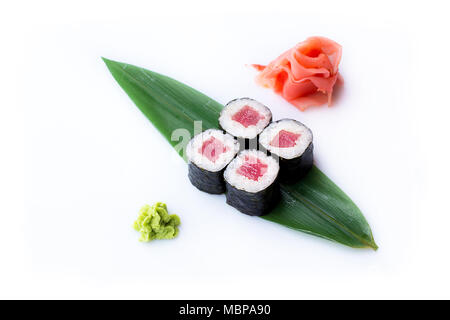 Delicious fresh mini-rolls with tuna on a banana leaf. Sushi rolls on a white background with ginger and wasabi. Stock Photo