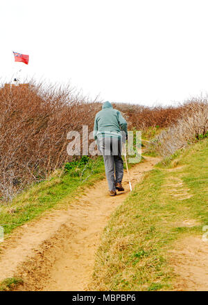 An elderly man with walking stick negotiating Skelding Hill on the Norfolk Coast Path at Sheringham, Norfolk, England, United Kingdom, Europe. Stock Photo