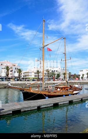 Wooden yacht moored along the river Bensafrim with waterfront buildings to the rear, Lagos, Algarve, Portugal, Europe. Stock Photo