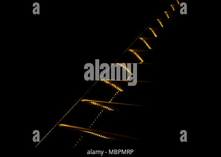 Contrast abstraction. Yellow lights and lines going diagonally upward on black background. Stock Photo