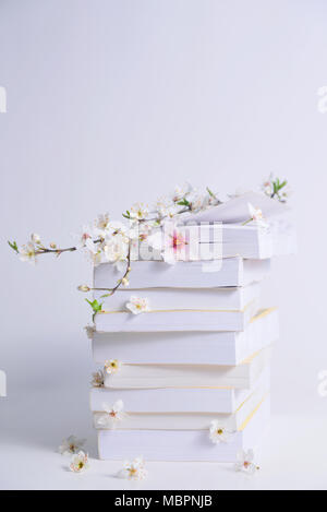 Stack of books with spring flowers between pages on a white background, concept reading