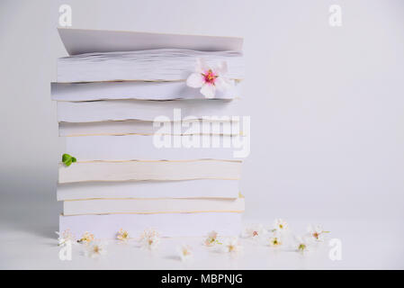 Stack of books with spring flowers between pages on a white background, concept reading, training